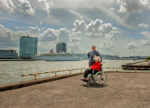 Older couple enjoying waterfront view in Amsterdam with cruise ship in the background.