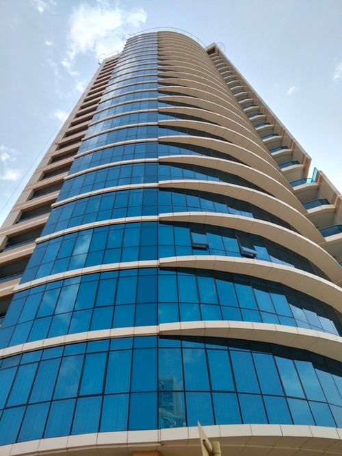 Free A towering modern skyscraper with a distinctive blue glass facade and curved design. Stock Photo