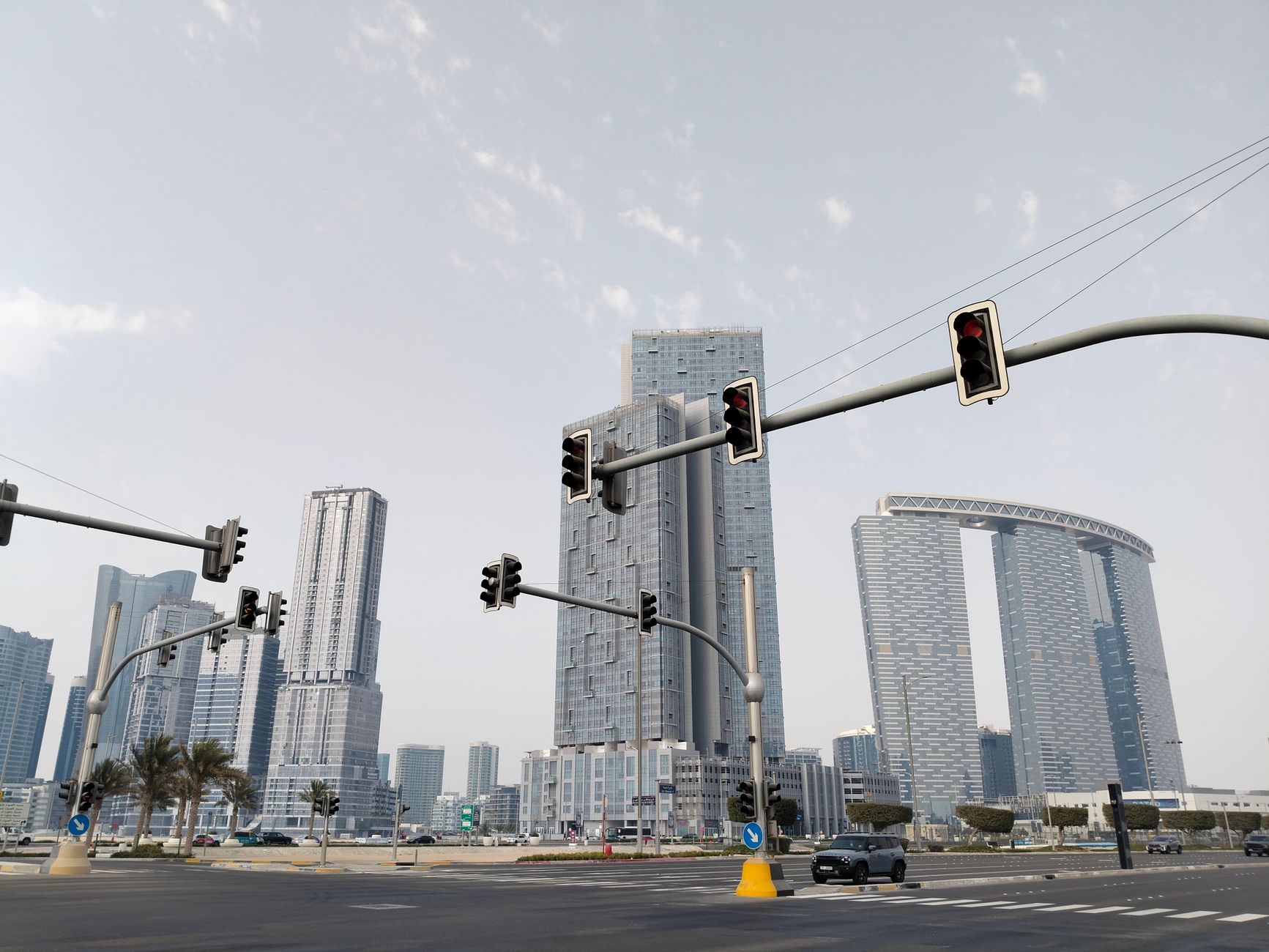 A city skyline with modern skyscrapers and traffic lights under a clear sky.