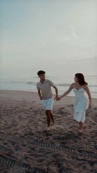 A couple enjoys a romantic stroll on a peaceful beach at sunset.