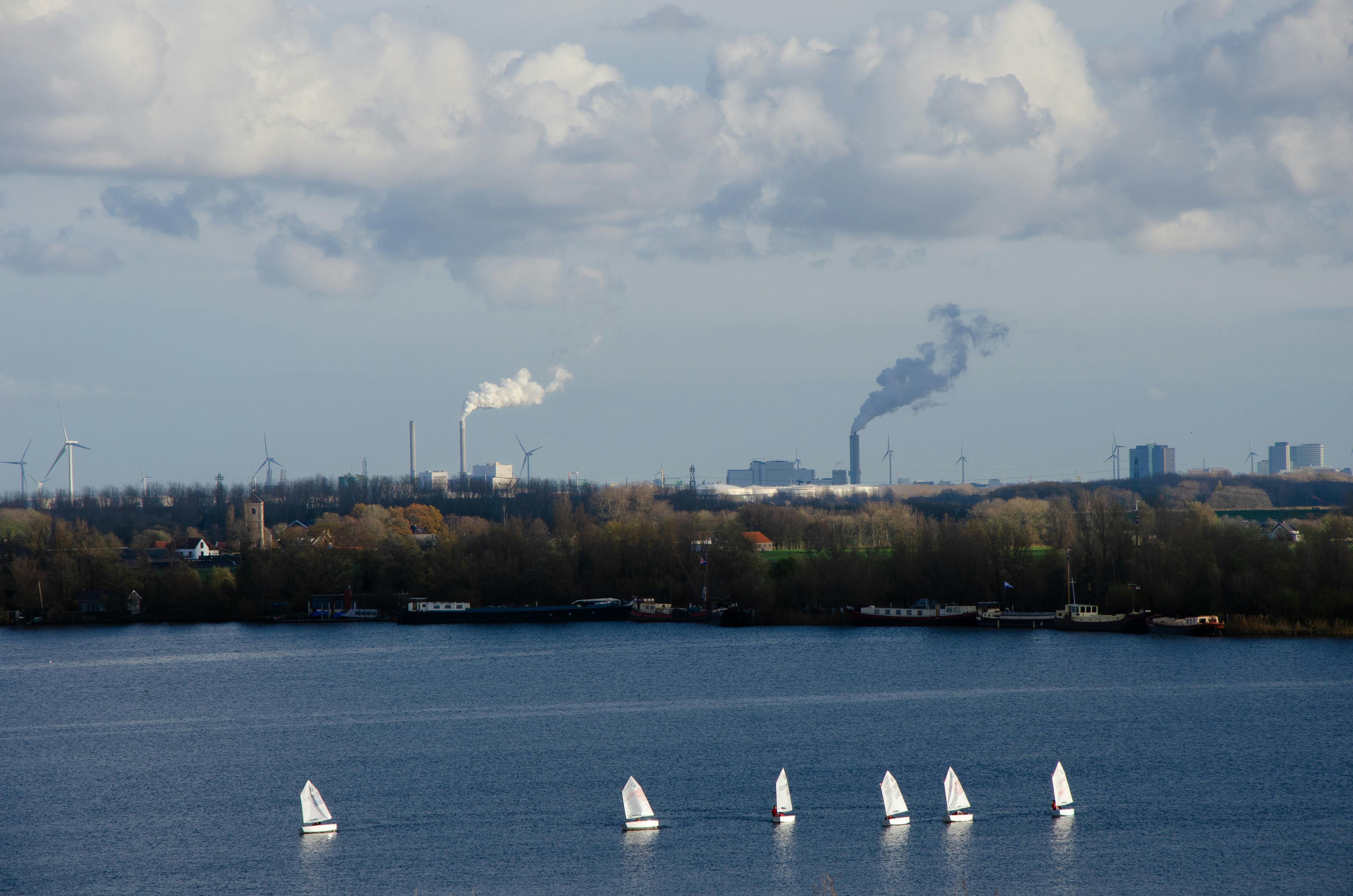 Sailing boats on a serene lake with an industrial skyline in Haarlem, Netherlands.