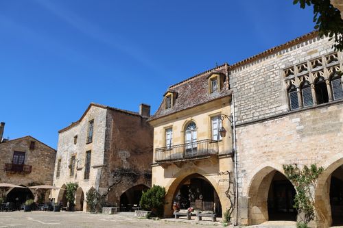 Free Picturesque stone buildings with arches in a historical town square under a clear blue sky. Stock Photo