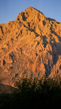 A stunning mountain peak illuminated by the warm glow of sunset, creating a dramatic and natural landscape.