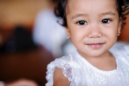 Free Charming portrait of a young child smiling, wearing a white dress. Close-up view. Stock Photo