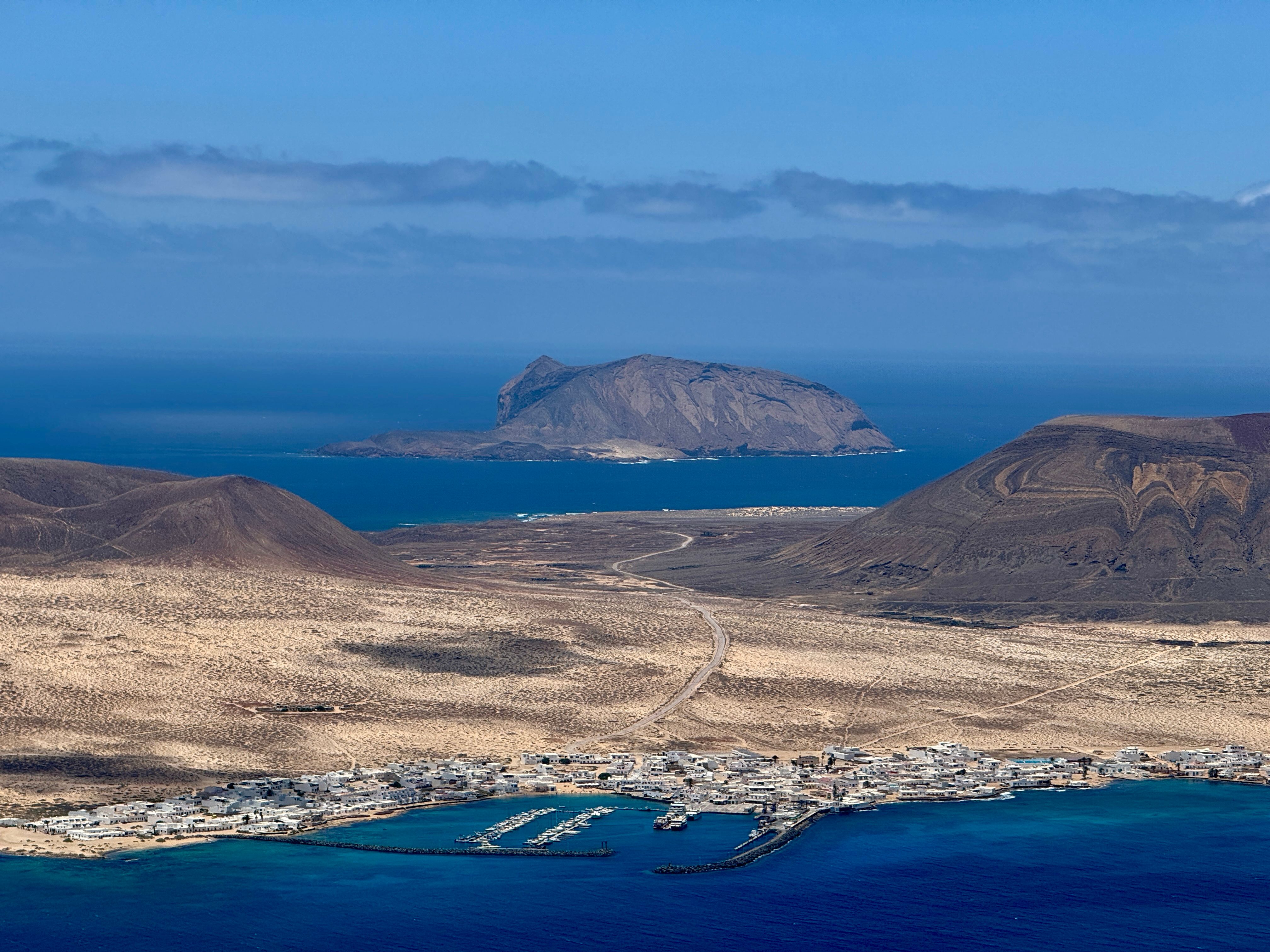 Explore Lanzarote's breathtaking landscapes with this stunning aerial view, featuring volcanic terrain and turquoise waters.