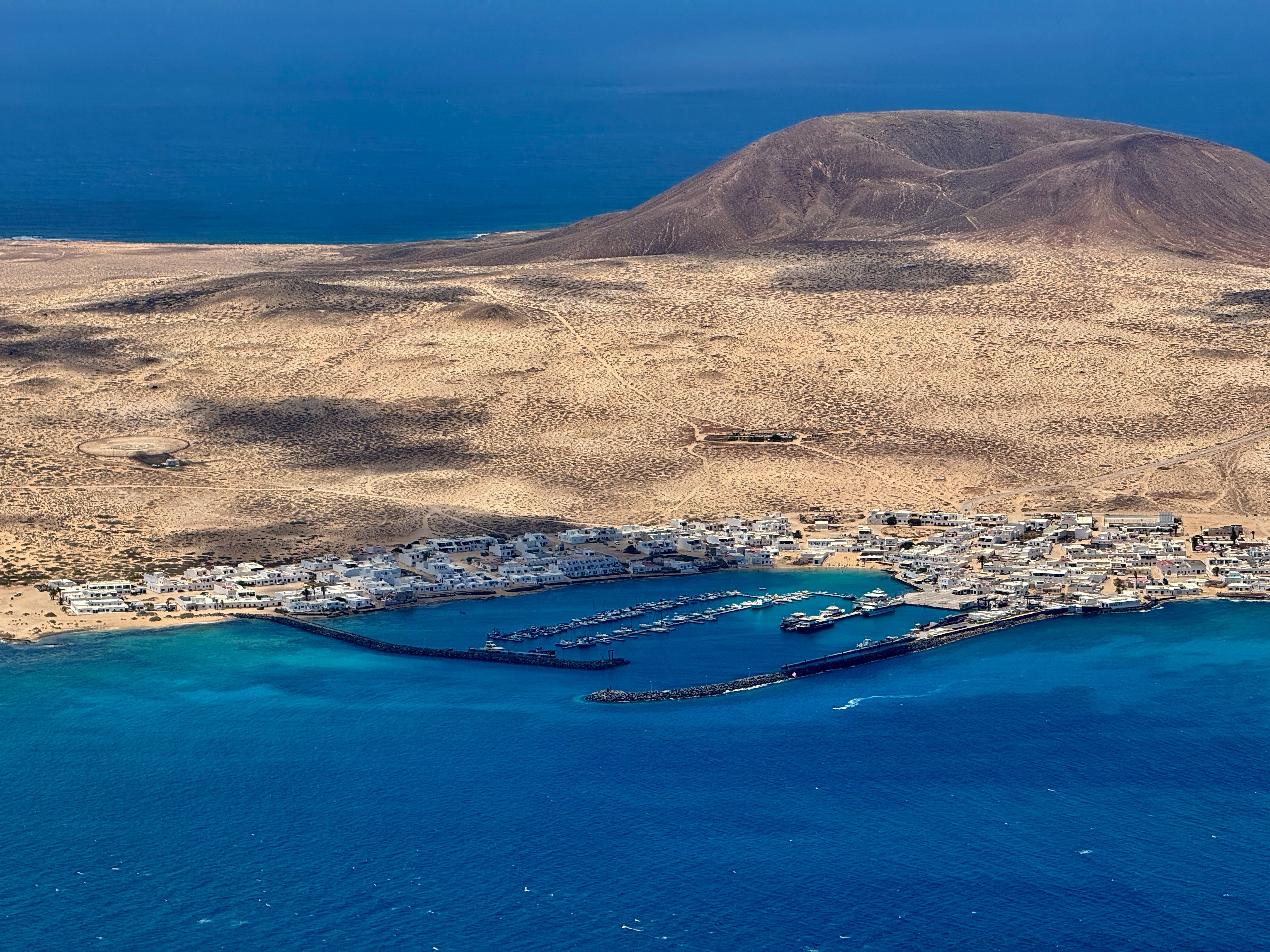 Stunning aerial shot of Lanzarote's coastal harbor and arid landscape under clear skies.