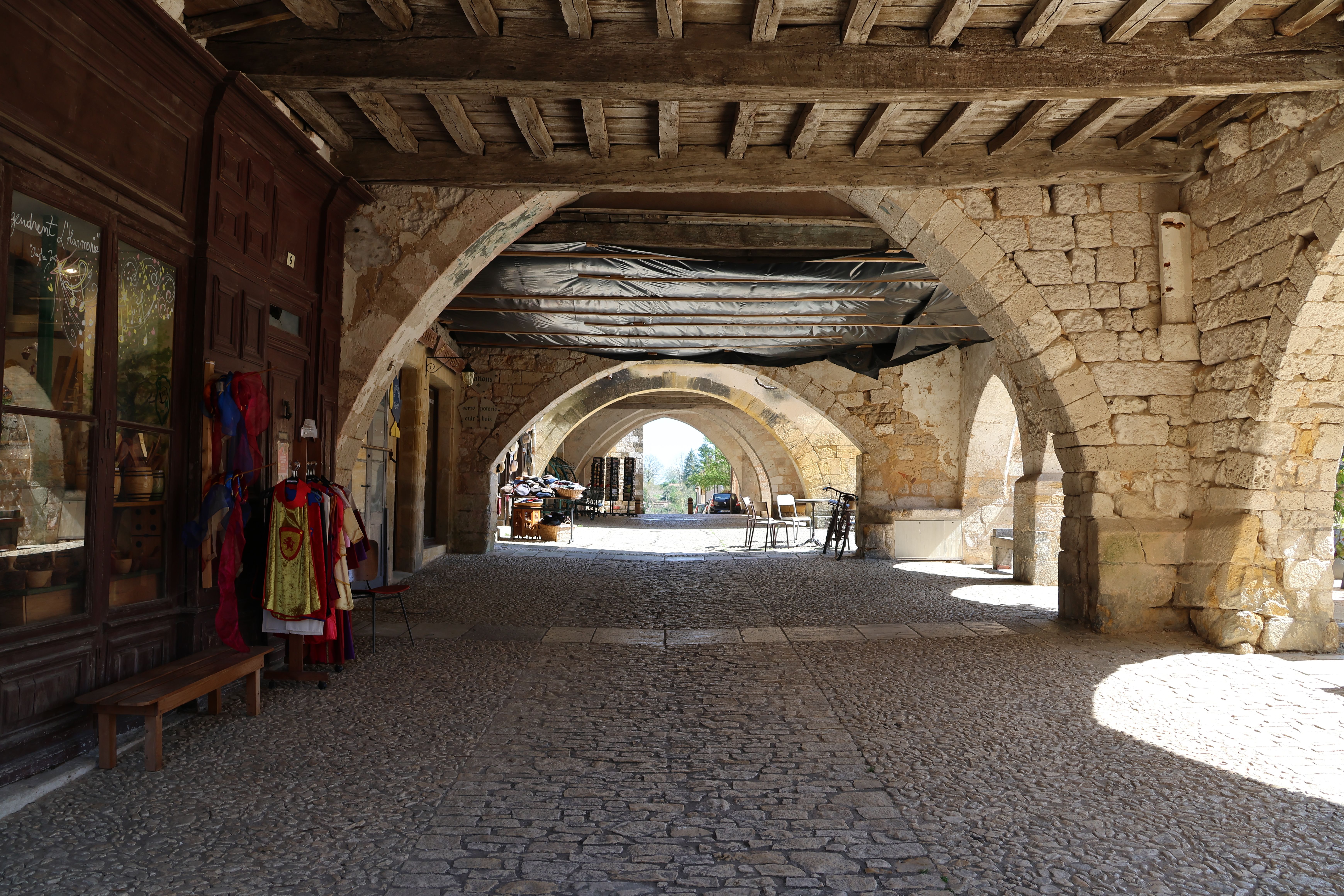 View of a medieval archway with cobblestone street and wooden beams, showcasing historic architecture.