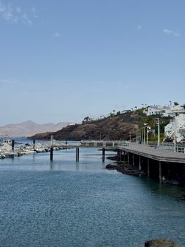 Explore the tranquil seaside of Puerto del Carmen, Lanzarote, featuring serene waters and modern architecture.