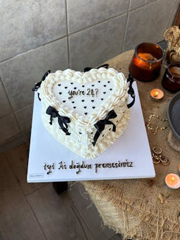 Elegant heart-shaped cake with candles and decorative bows, perfect for celebrations.