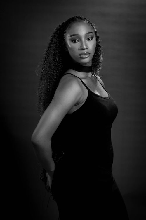 Free Elegant black woman posing confidently in black attire under studio lighting. Stock Photo