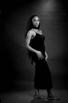Striking black and white portrait of a woman in a long dress, exuding elegance and poise.