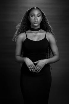 Elegant black and white portrait of a woman with curly hair, exuding poise and confidence.
