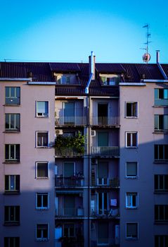 A contemporary apartment building in Milan, Italy, with balconies under a bright blue sky.
