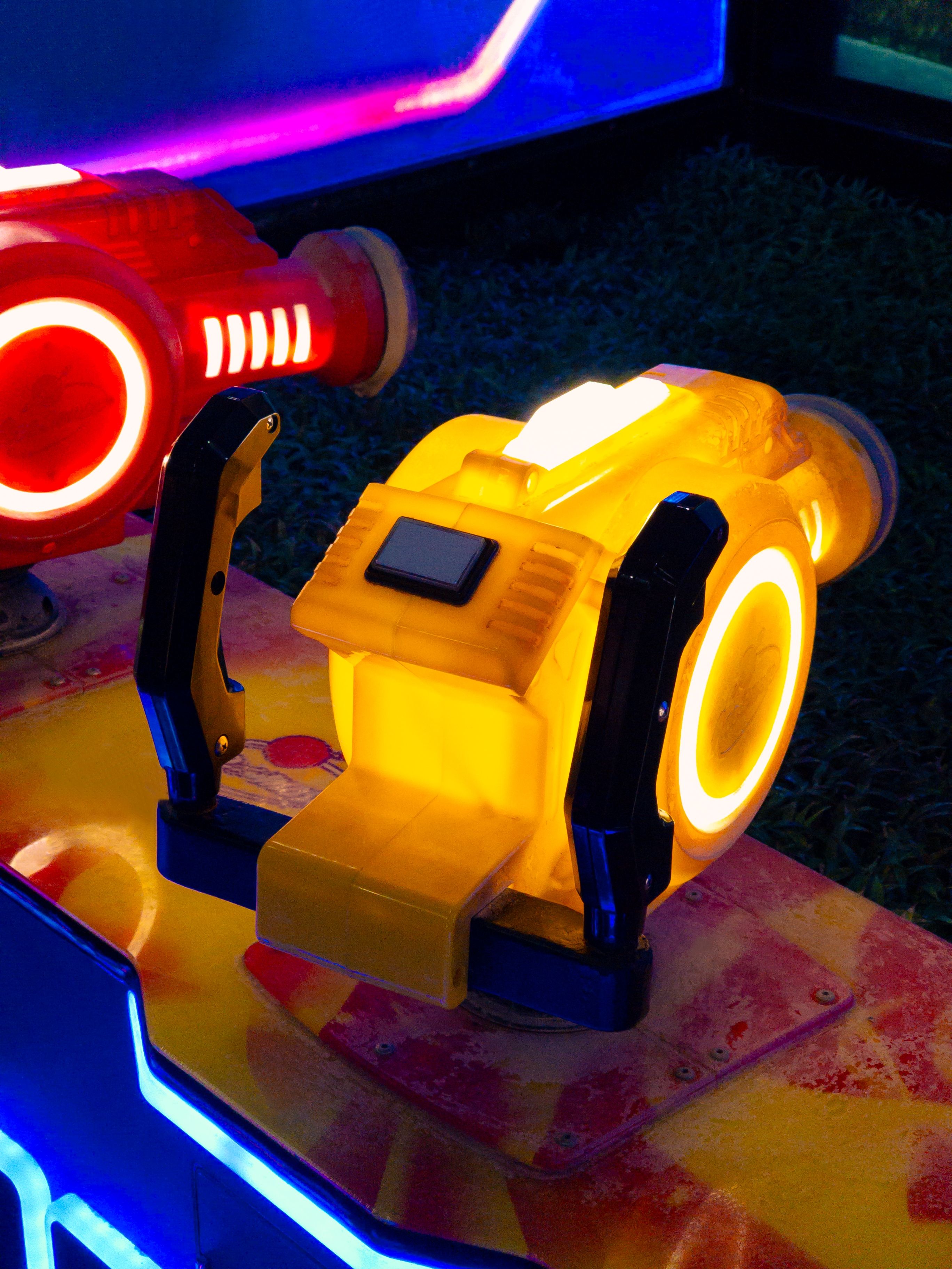 Close-up of an amusement ride with vibrant neon lights in yellow and red tones.