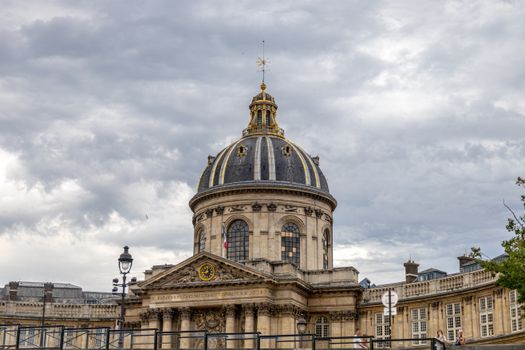 Architectural view of the iconic dome at the Institute of France in Paris under cloudy skies.