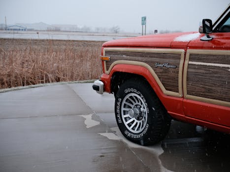Close-up of a vintage red Grand Wagoneer parked outdoors in Pontiac, Illinois, during winter snowfall.