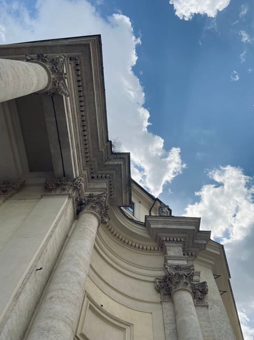 Free Low-angle view of baroque architecture with ornate columns against a bright blue sky. Stock Photo