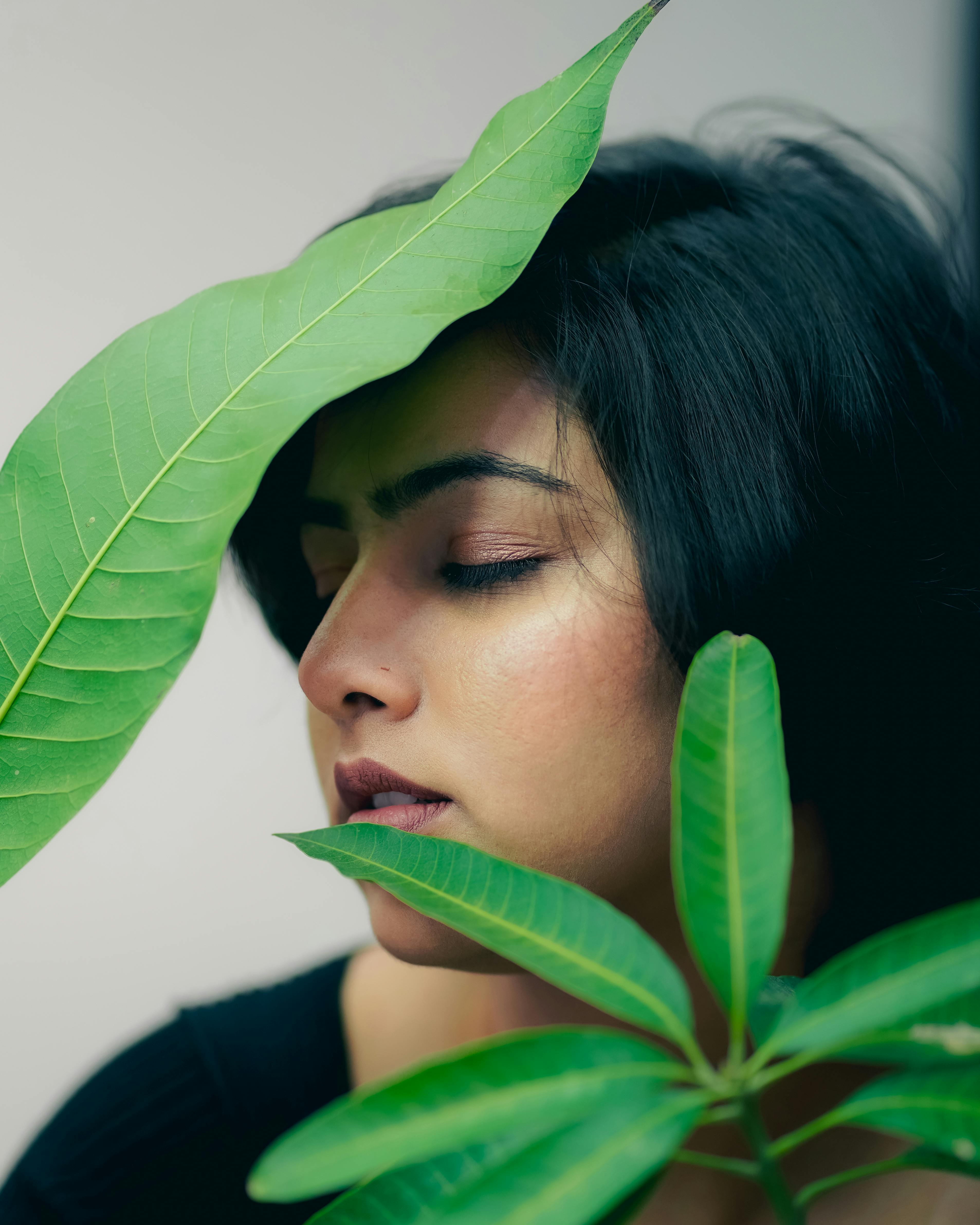 Elegant portrait of a woman surrounded by lush green foliage, exuding tranquility.