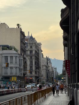 Vibrant street life in Barcelona with historic architecture under a sunset sky.