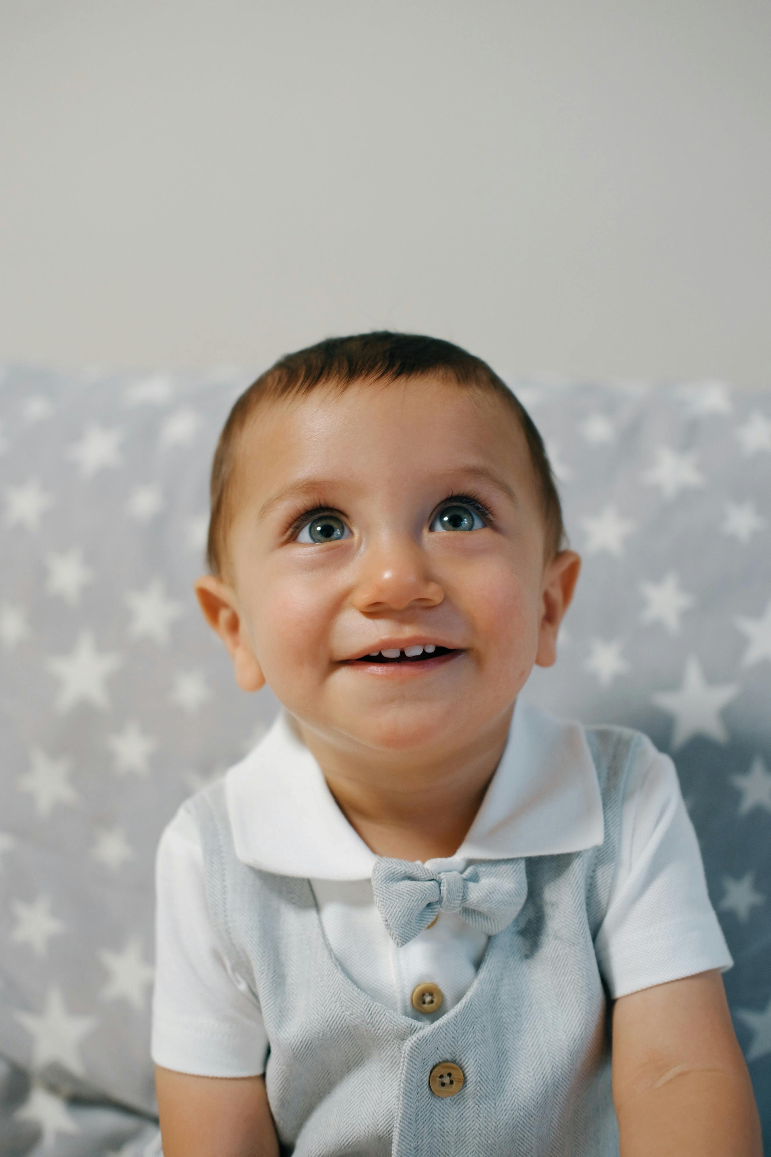 Charming portrait of a baby smiling indoors against a starry patterned background, Aydın, Türkiye.