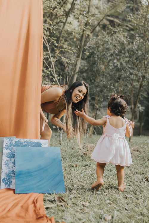 Free A joyful mother and child play outside, surrounded by colorful art pieces. Stock Photo