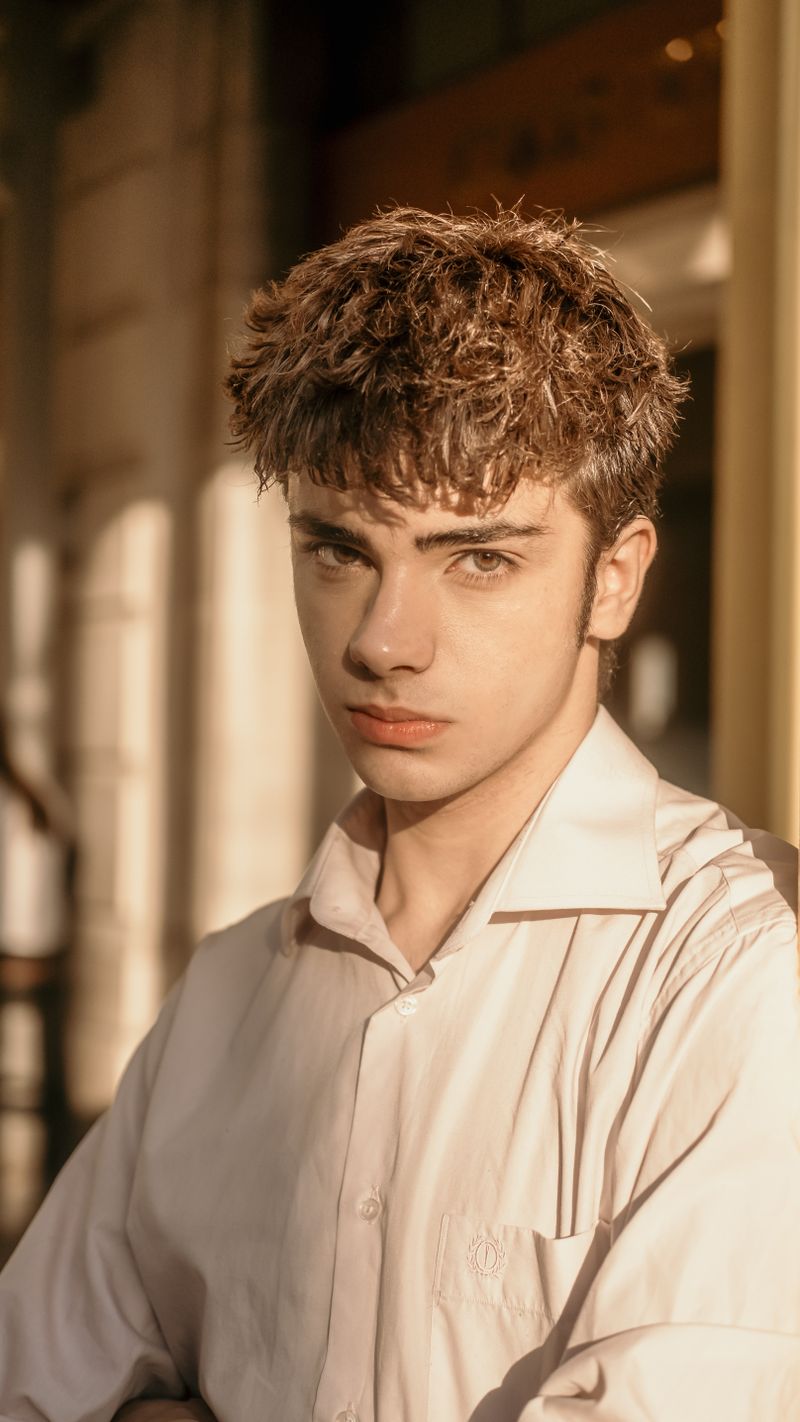 Stylish portrait of a young man bathed in warm sunlight, set outdoors.