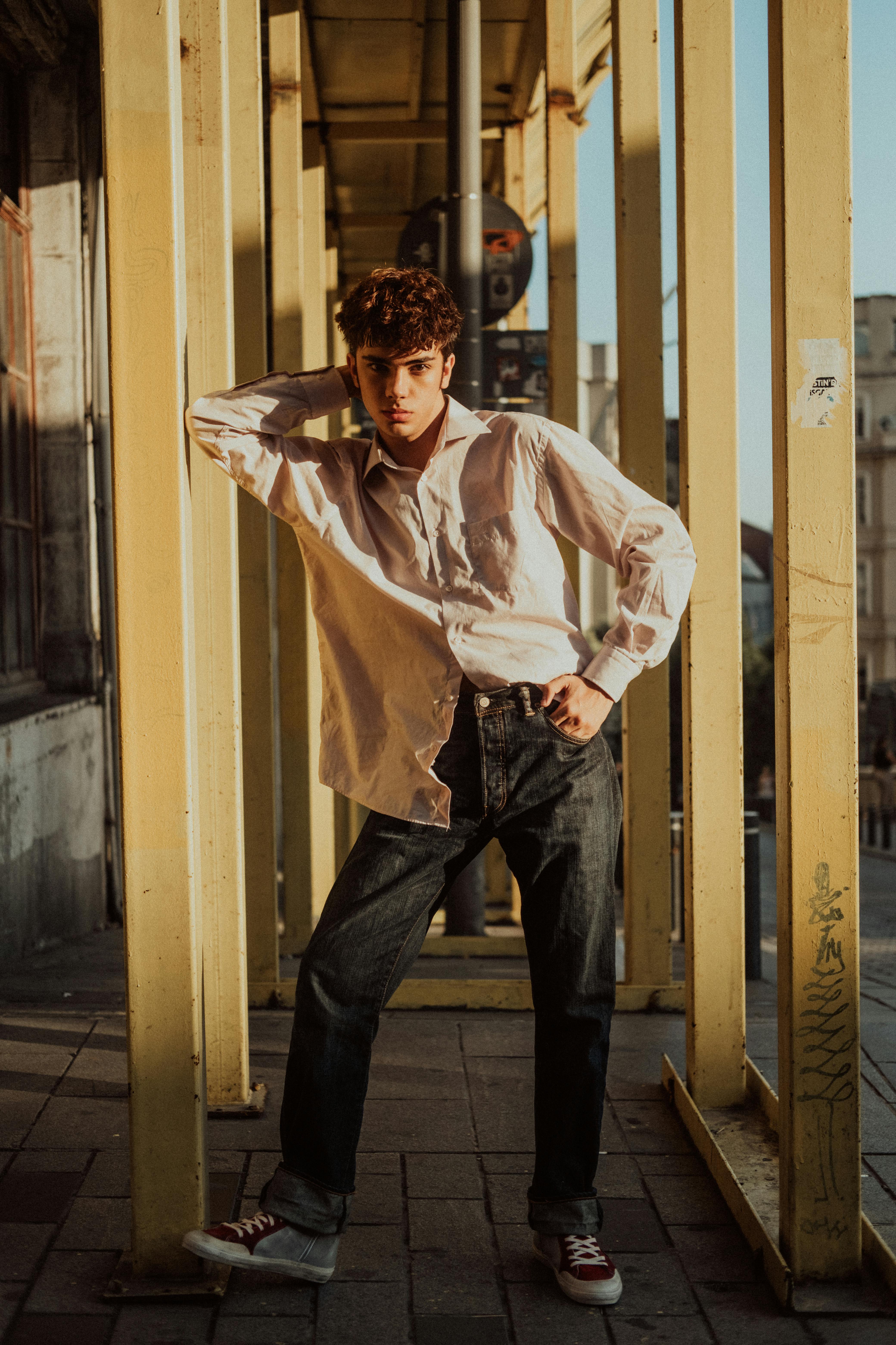 Male model posing in an urban outdoor setting in İstanbul, showcasing modern fashion and architecture.