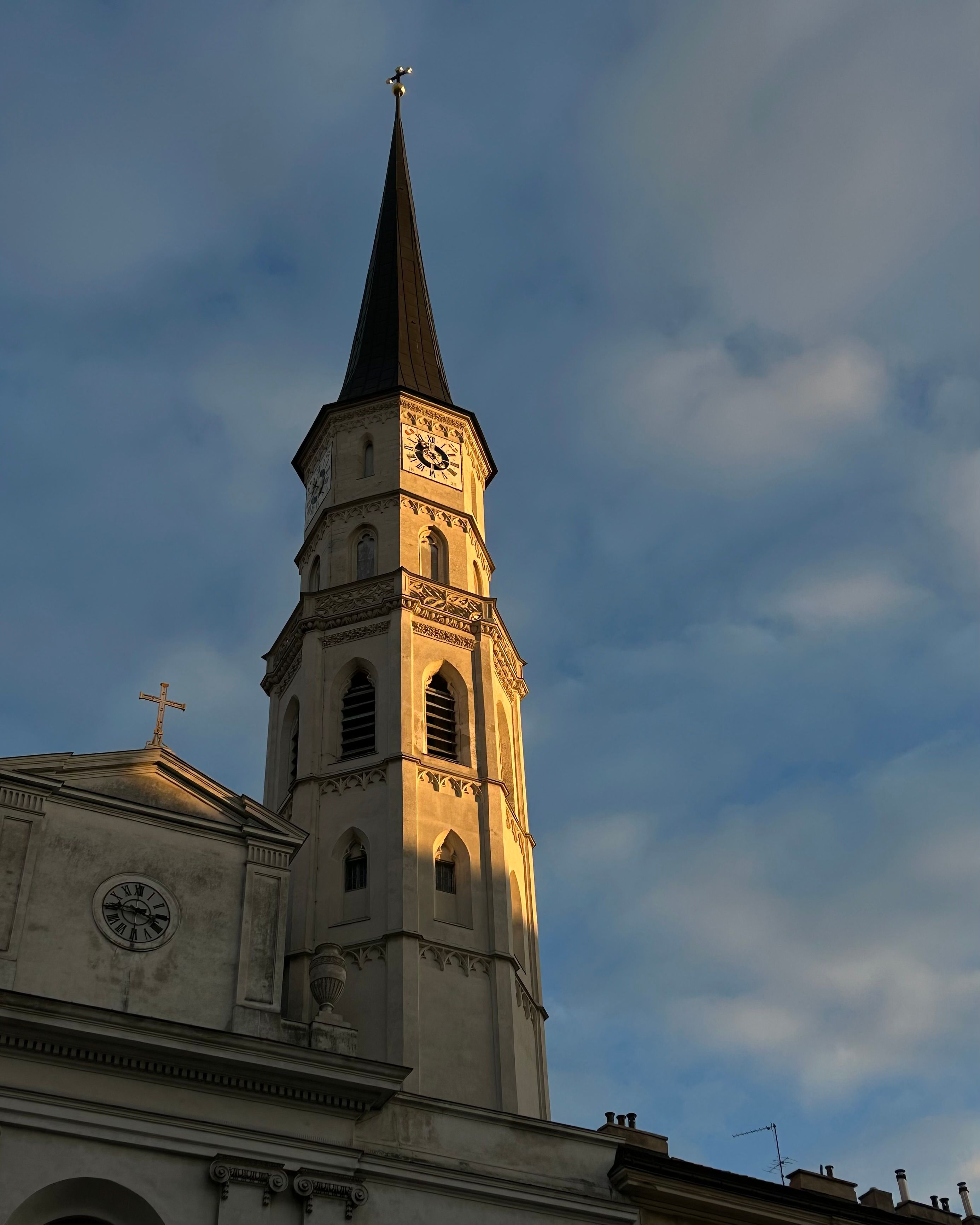 A beautiful church tower bathed in warm sunset light against a cloudy sky, showcasing architectural elegance.