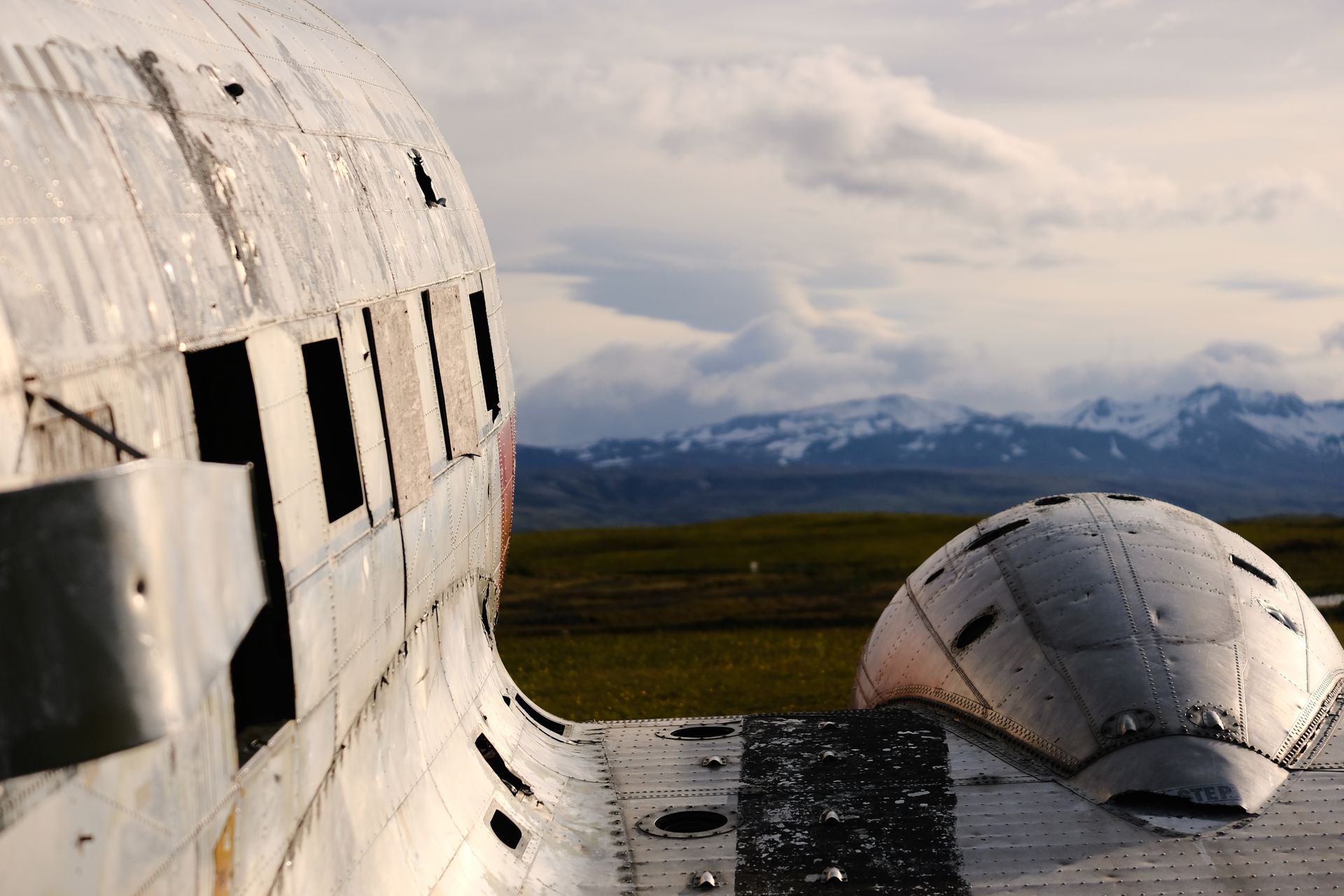 Abandoned aircraft fuselage on a remote island with mountain backdrop, evoking mystery and adventure.