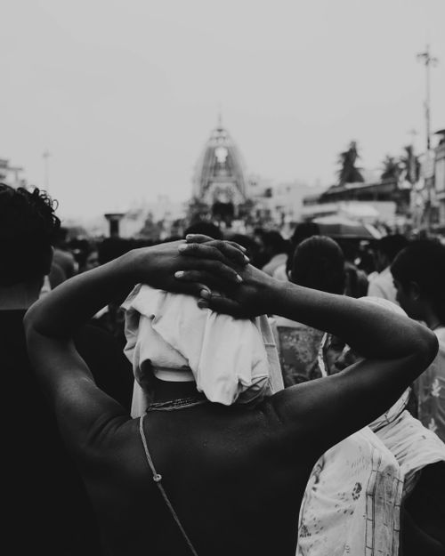 Free Black and white image of a crowded cultural festival with a focus on a person facing away, wearing a headwrap. Stock Photo