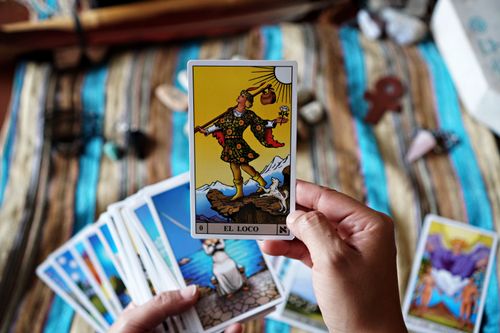 Free A person holds a tarot card 'El Loco' with a background of more cards, symbolizing fortune telling. Stock Photo