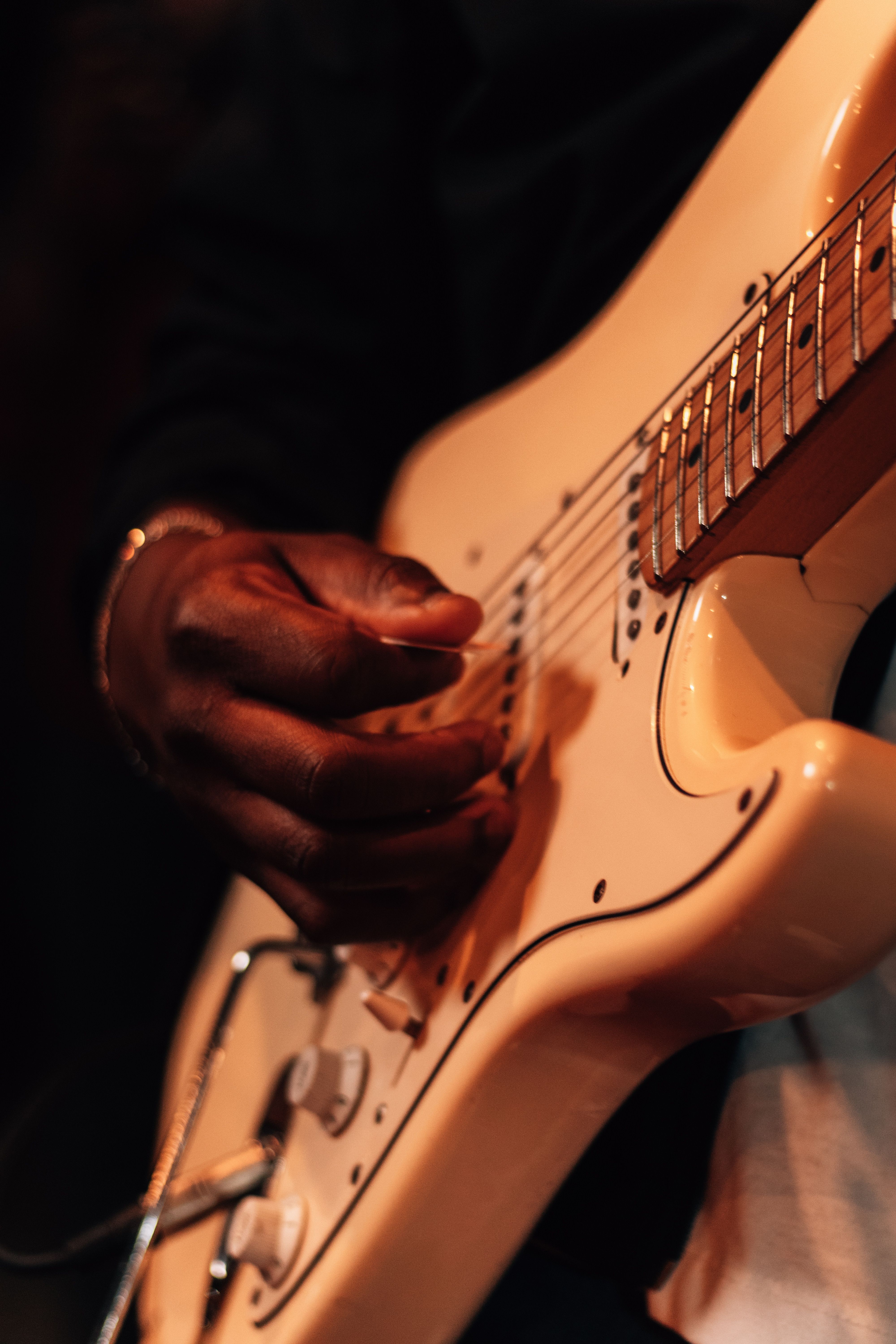 Close-up of a musician playing a white electric guitar, focusing on the guitar strings and hands.. close, musician, playing