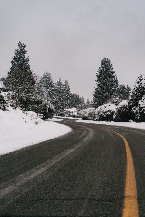 Free A scenic snow-covered road curves through a winter landscape in West Vancouver, Canada. Stock Photo