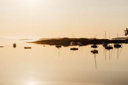 Free Serene sunrise over Oak Bay, British Columbia with boats reflecting on calm waters. Stock Photo