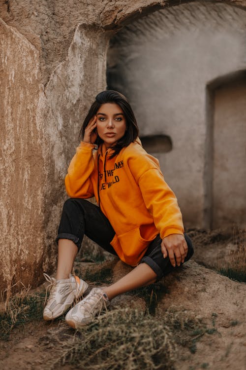 Wanita Mengenakan Hoodie Pullover Oranye Dan Celana Capri Hitam