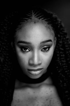 Elegant black and white portrait of a woman with braided hair and intense gaze.