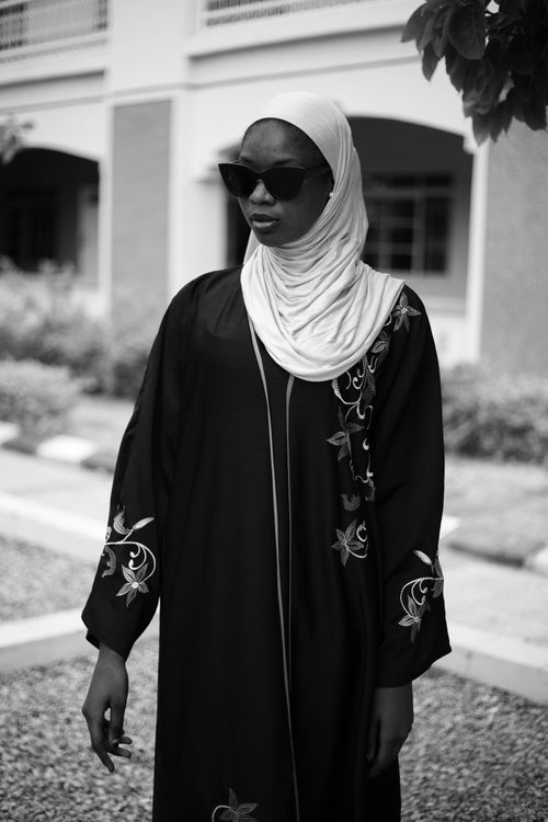 Free Elegant woman wearing sunglasses and a black hijab with embroidery standing outdoors. Stock Photo