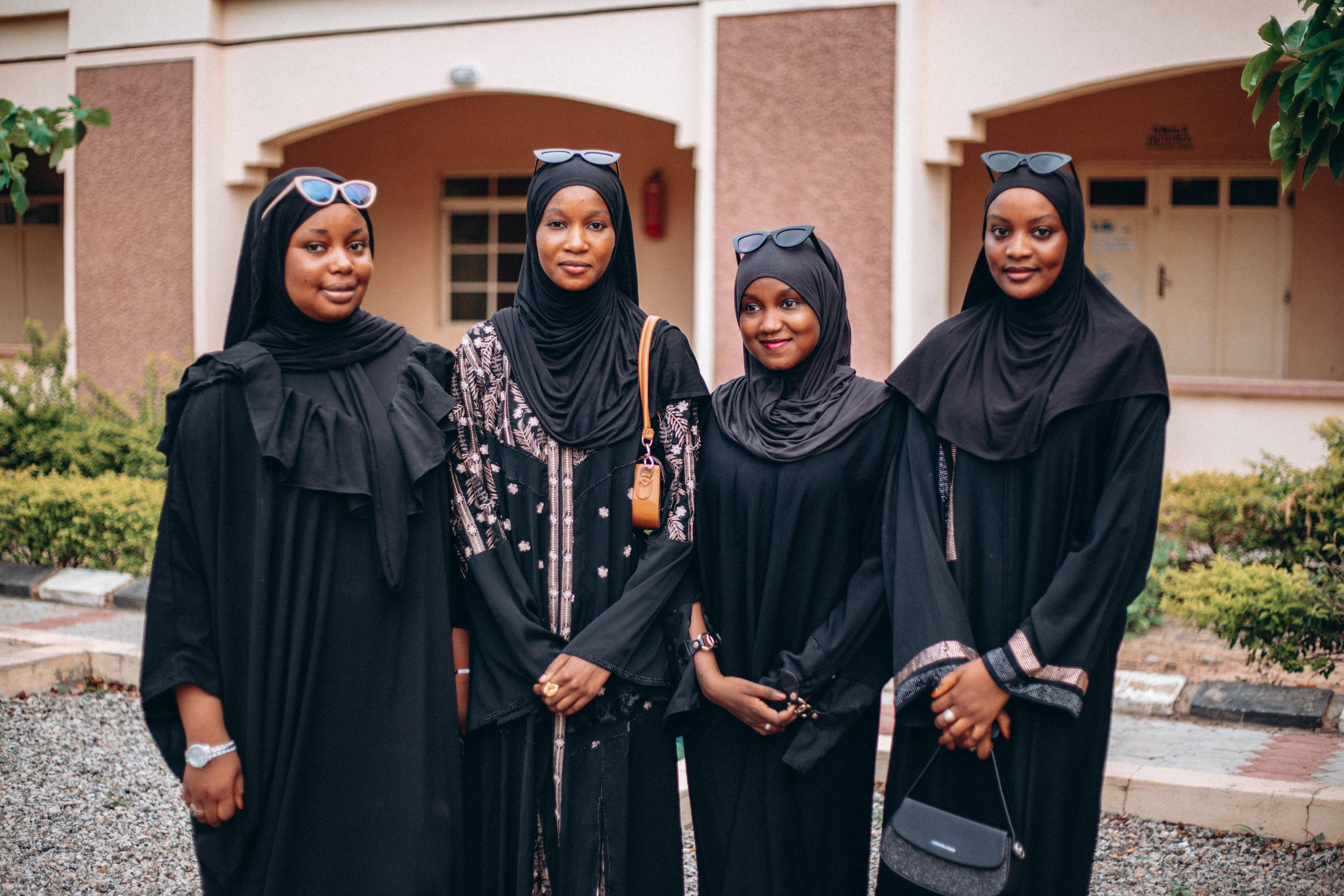 women green abaya headscarf set - Smiling women in black hijabs and abayas standing outdoors.