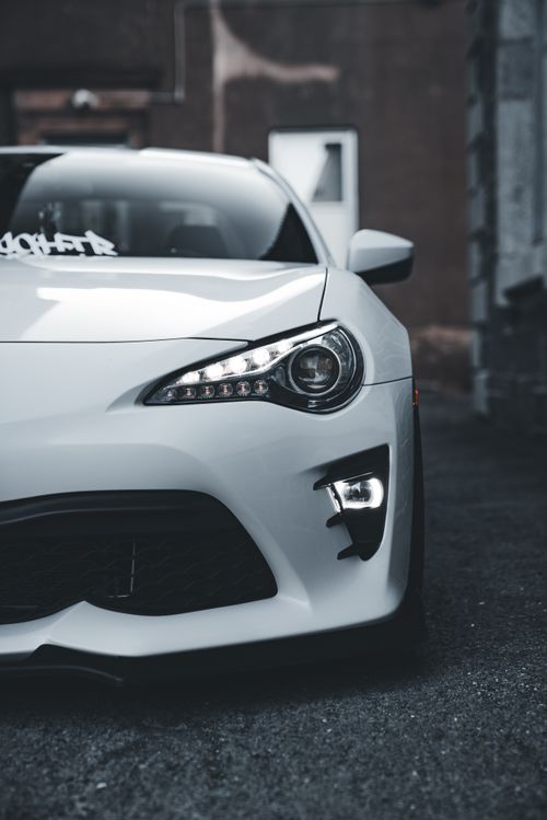 Free High-contrast image of a modern white sports car parked on a dark urban street. Moody and dramatic lighting. Stock Photo