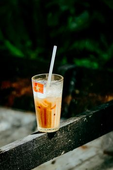 A refreshing glass of Vietnamese iced coffee with milk, resting on a rustic outdoor table.