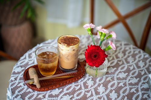 Free Iced coffee and tea with floral decor on a patterned table, perfect mix of comfort and aesthetics. Stock Photo
