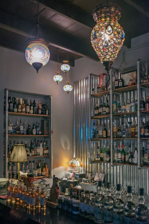 Free Warm and inviting bar interior with colorful lamps and an array of bottles on display. Stock Photo