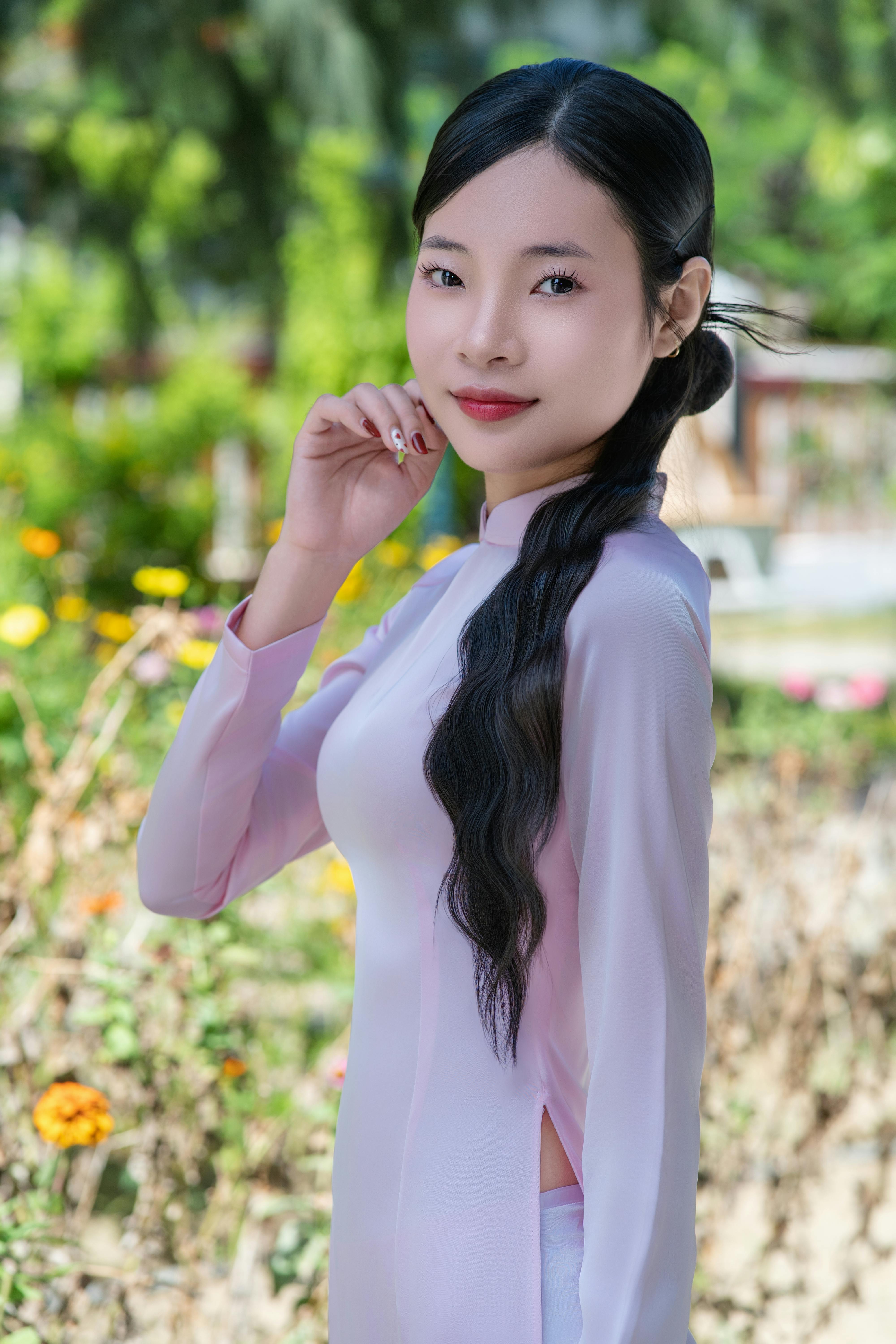 Portrait of a young woman in a pink traditional dress enjoying a sunny day in a garden.