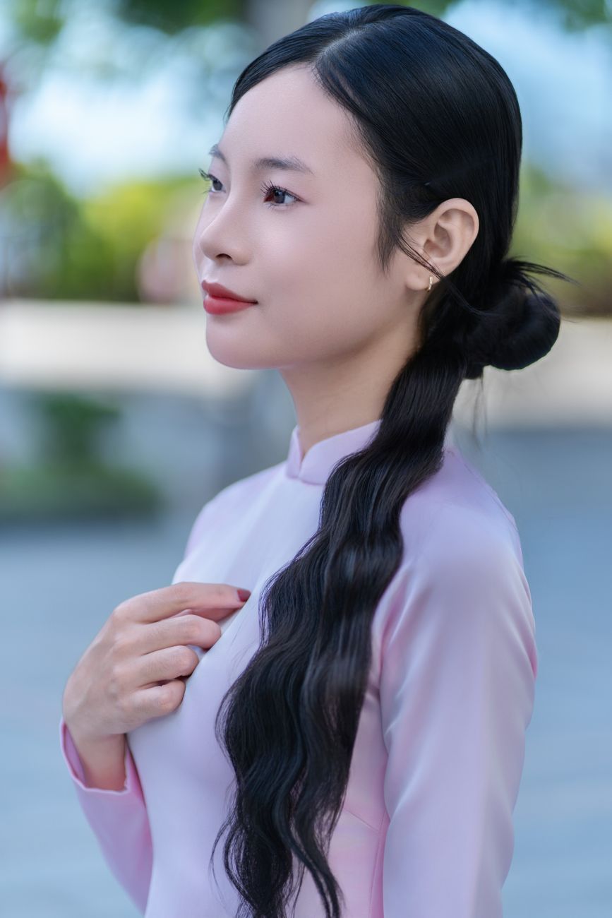 Side profile of a woman in a pink traditional dress outdoors on a sunny day.
