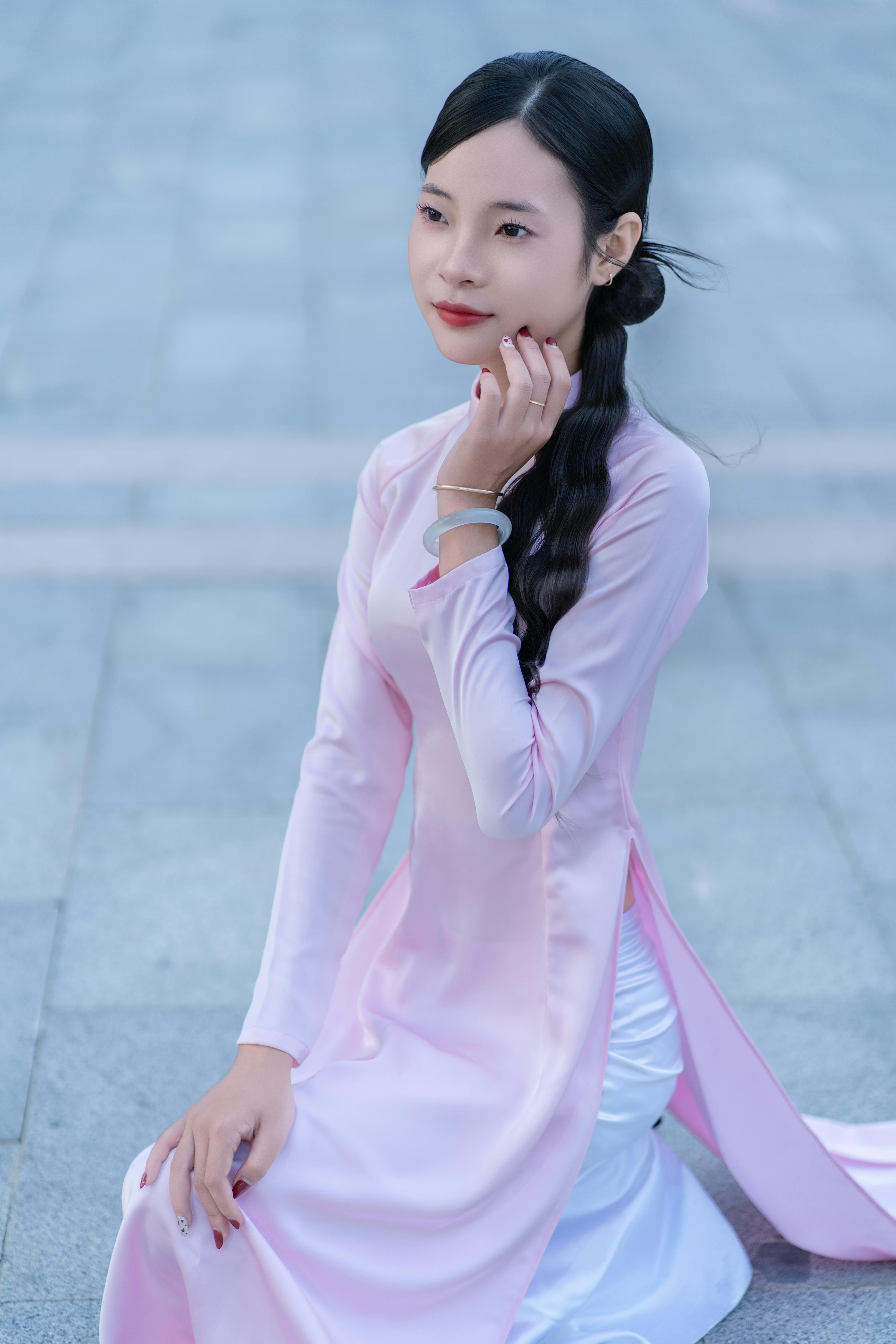 Portrait of a woman in a pink Áo dài sitting, showcasing elegance and tradition.
