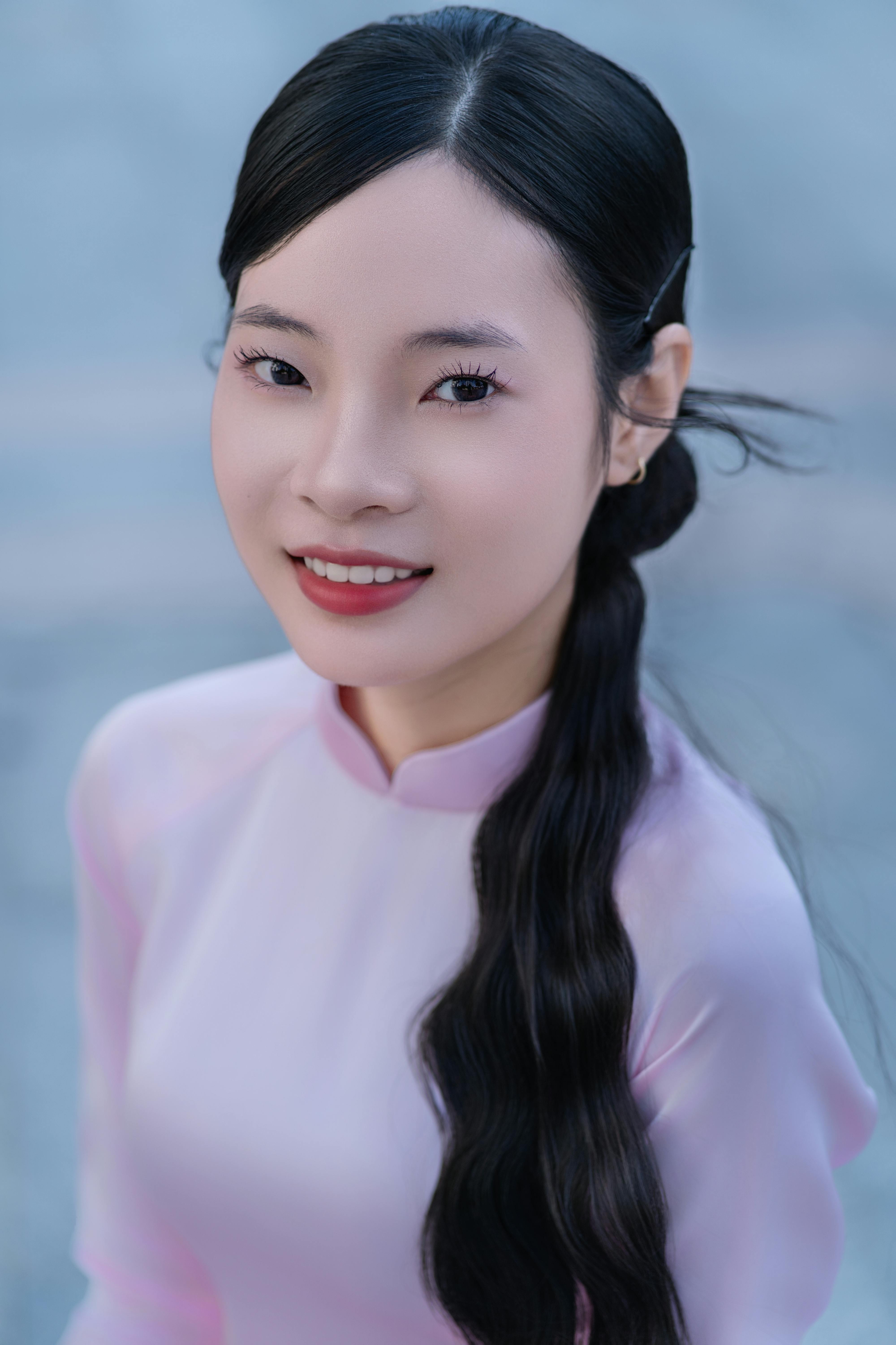 Smiling woman in a traditional pink dress, looking elegantly at the camera.