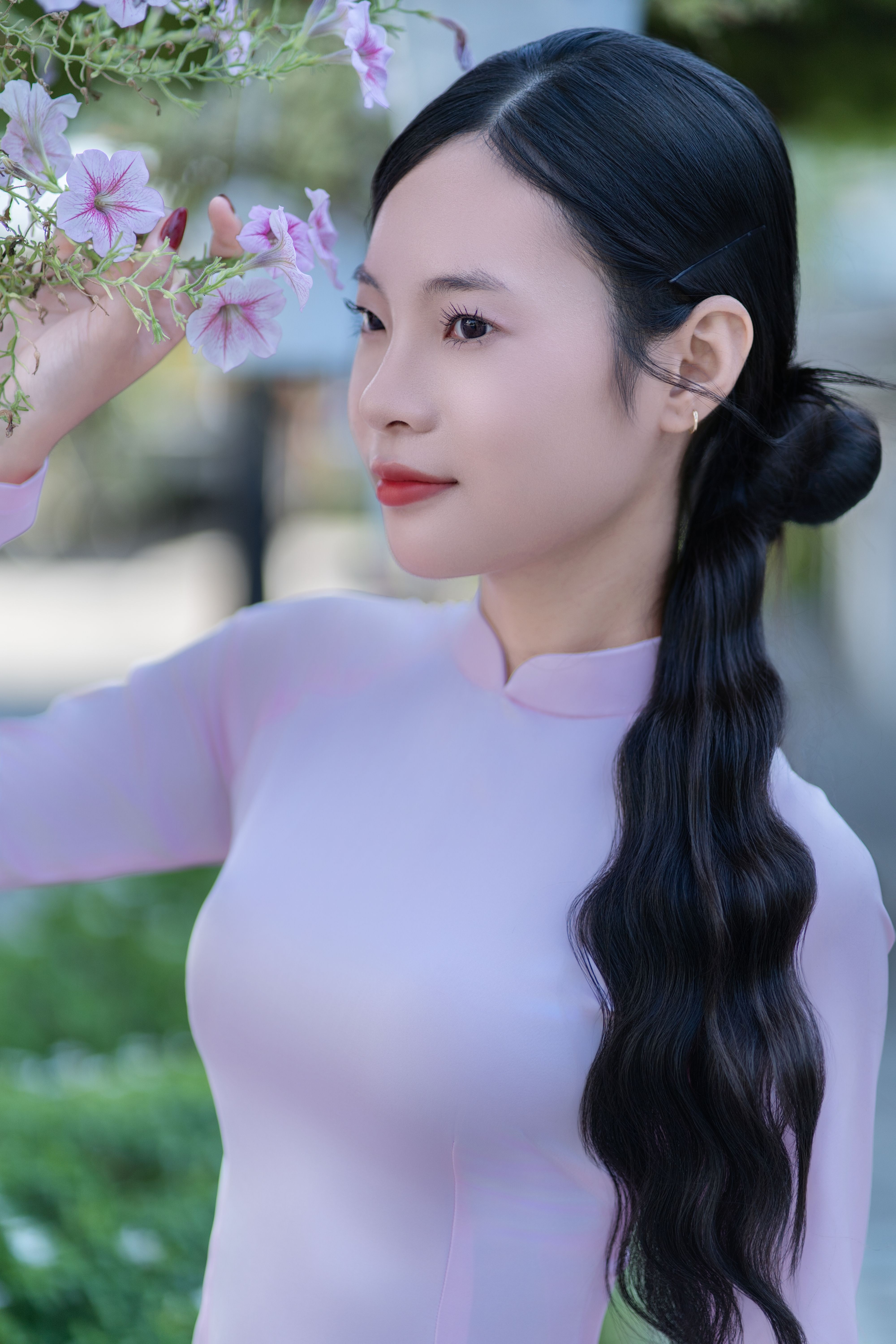 Woman in pink traditional dress with flowers, outdoors. Elegant and serene.