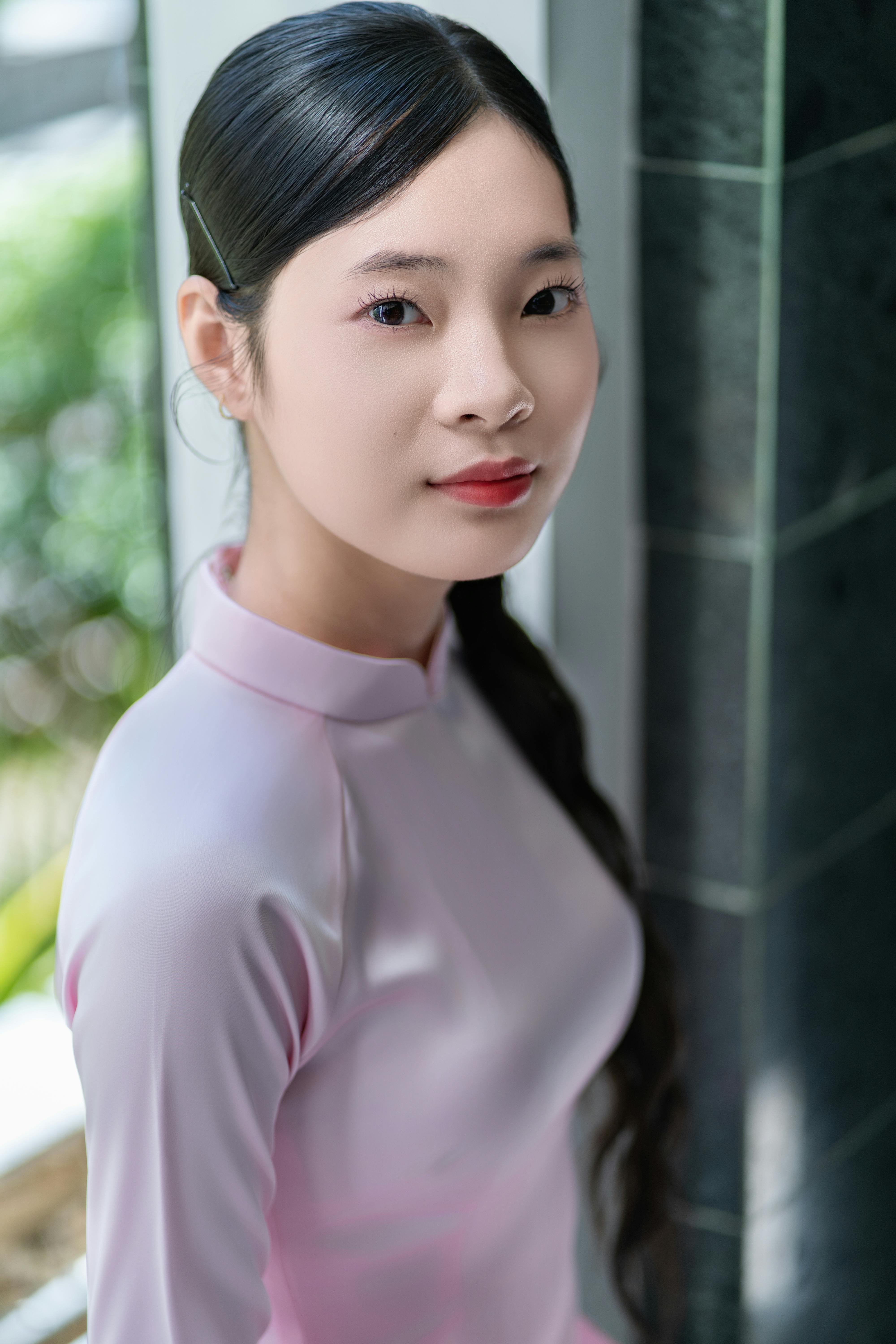 Portrait of a woman in traditional pink Ao Dai indoors with natural light.
