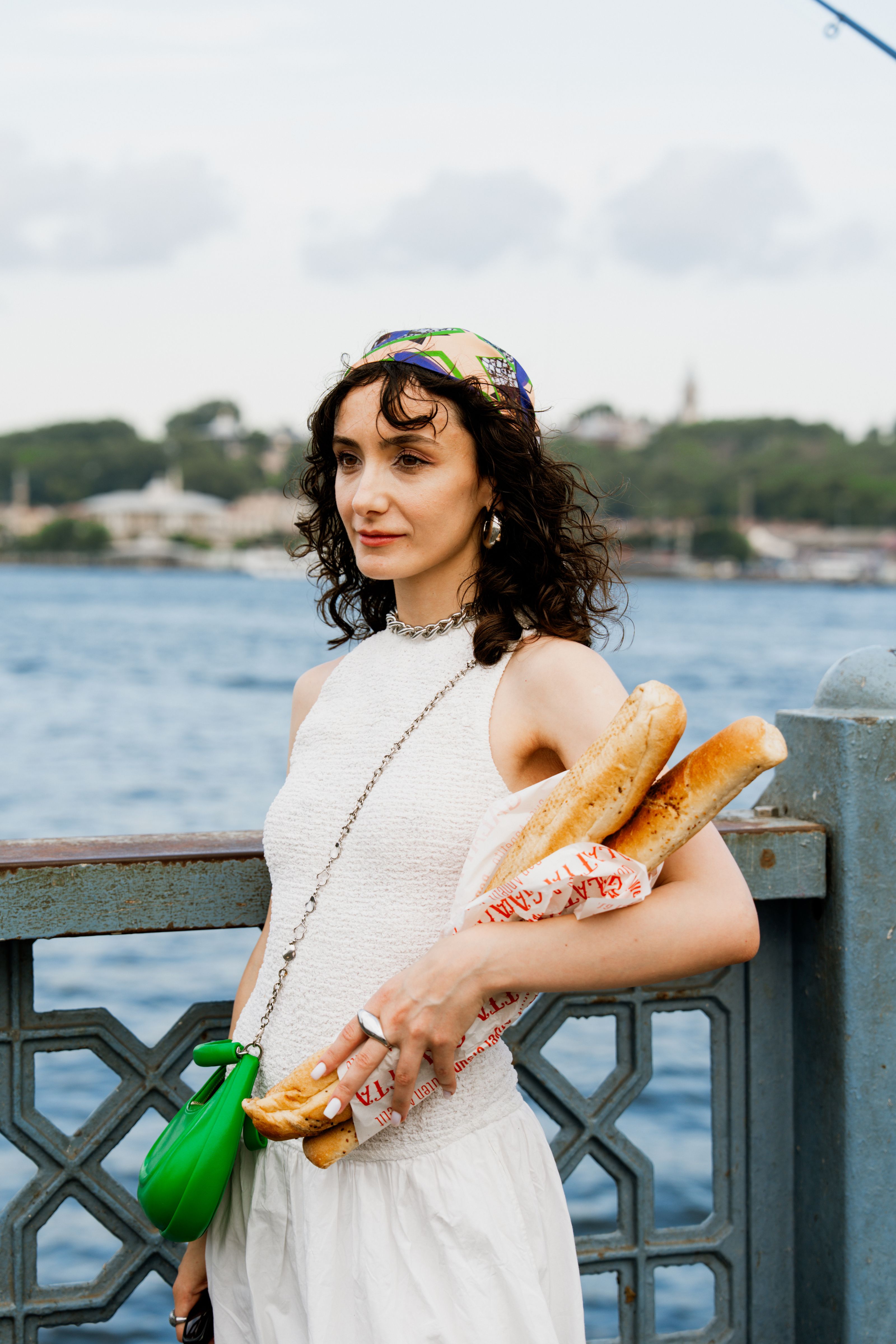 Mulher estilosa com baguetes à beira de um rio, exalando charme parisiense.