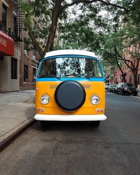 Front view of a vibrant classic VW van parked on a tree-lined street in NYC.